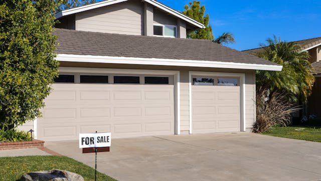 grey house with a for sale sign out front